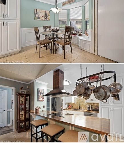 A kitchen with a table and chairs and a kitchen island with a hanging pot rack.