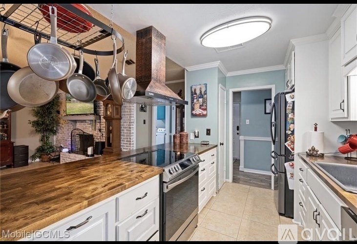 A kitchen with a wooden counter top and white cabinets.