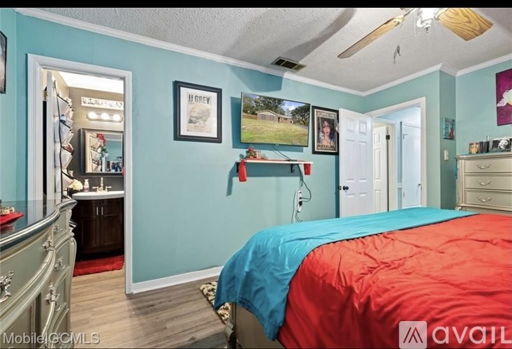 A bedroom with a red bedspread and a blue wall.