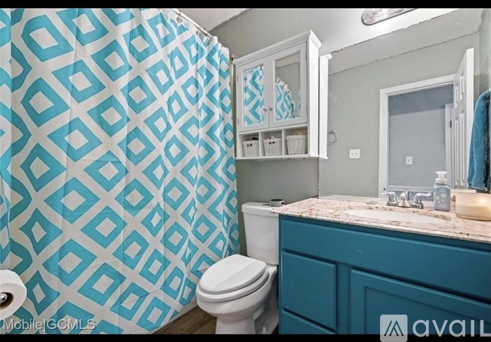 A bathroom with a blue and white shower curtain and a white toilet.