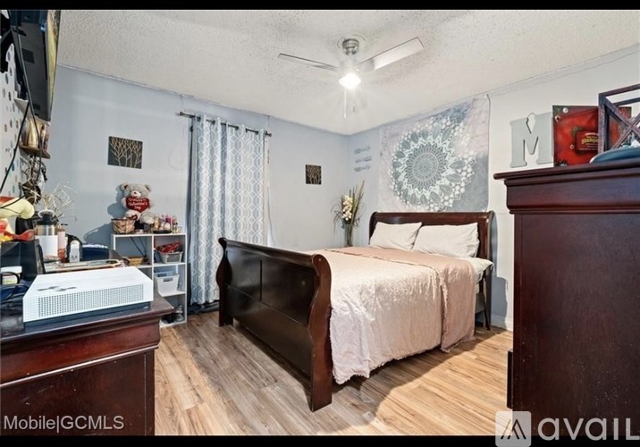 A bedroom with a bed, dresser, and a ceiling fan.