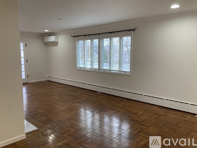 A room with wooden flooring and a window with blinds.