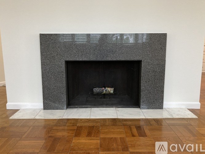 A grey fireplace with a black fire grate in the middle.