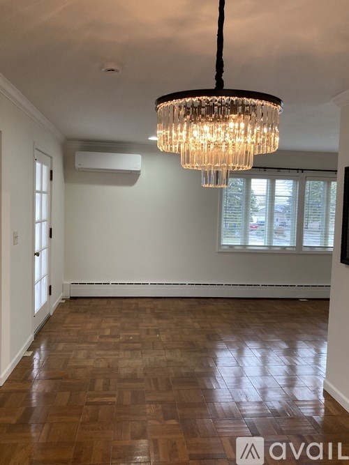 A room with wooden flooring and a chandelier hanging from the ceiling.