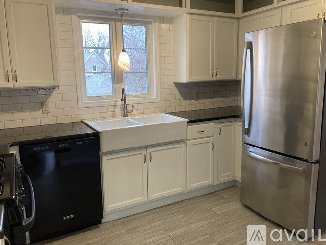 A kitchen with white cabinets and a black fridge.
