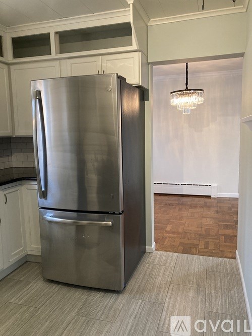 A stainless steel refrigerator in a kitchen with white cabinets.