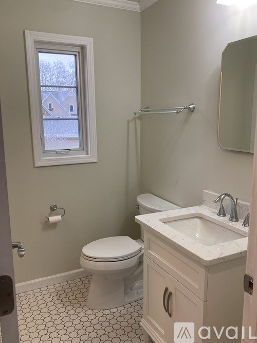 A bathroom with a toilet, sink, and a window.