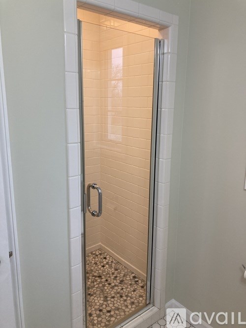 A shower stall with a glass door and a handle.