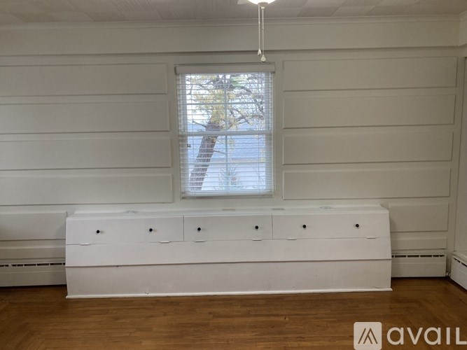 A white cabinet with a window above it in a room.