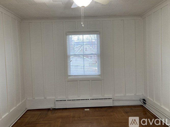 A room with white walls and a window with blinds.