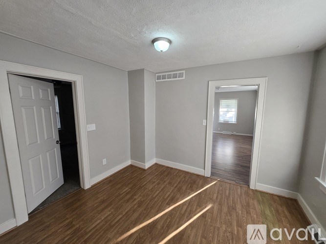 A room with wooden flooring and two doors, one of which is open.