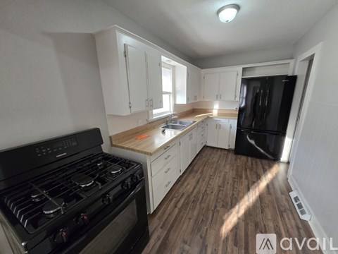 A kitchen with a black stove top oven and white cabinets.