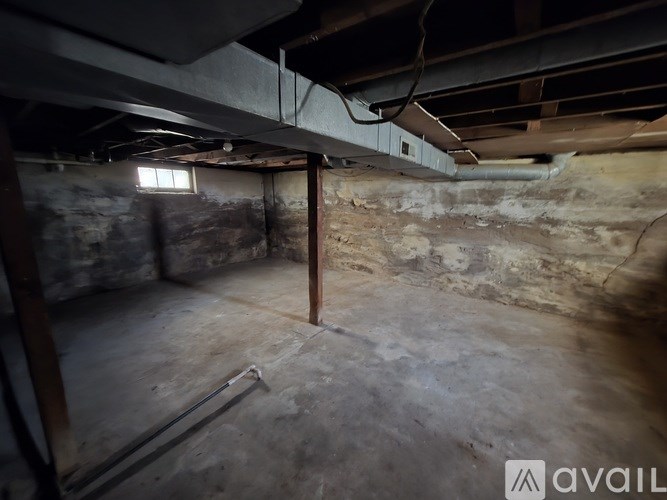 A room with a concrete floor and walls, and a window on the left side.