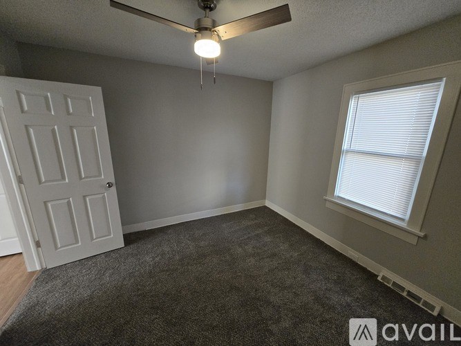 A room with a ceiling fan, a door, and a window.