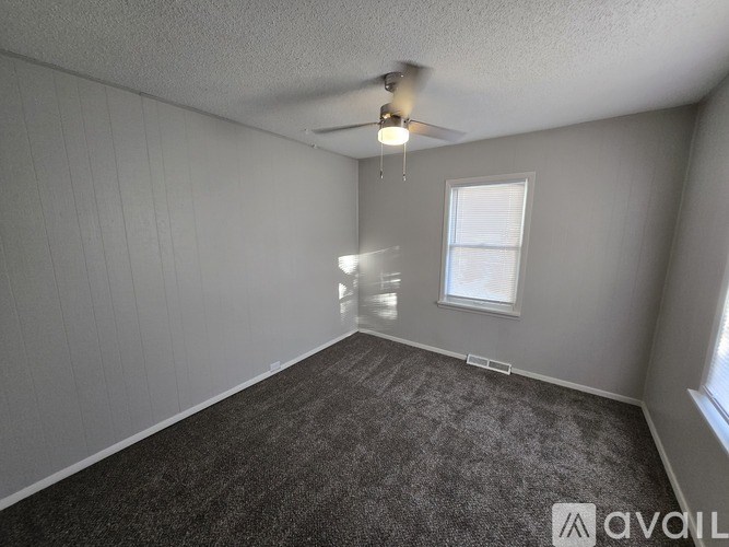 A room with grey carpet and a window.