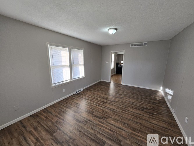 A room with wooden flooring and two windows is available for rent.