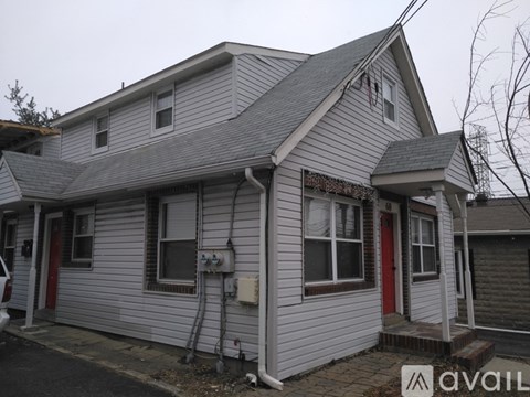 A house with a red door and a grey siding is for sale.