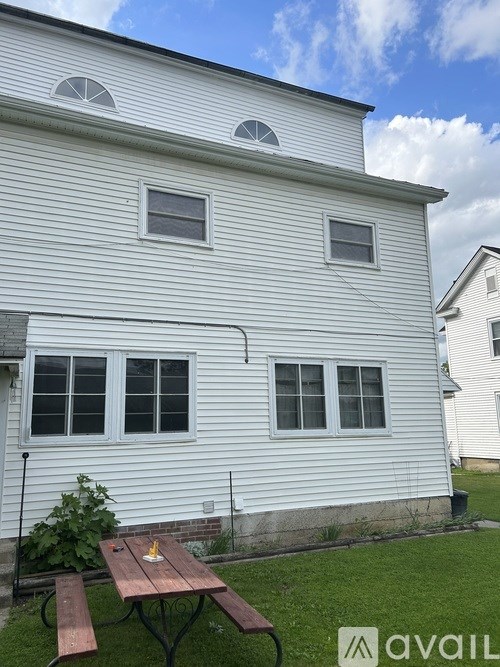 A white house with a picnic table in front.