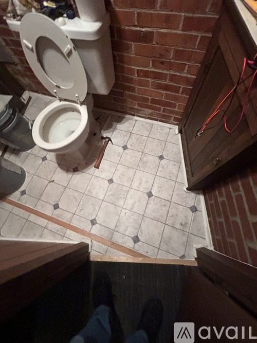 A toilet is installed in a bathroom with a brick wall.