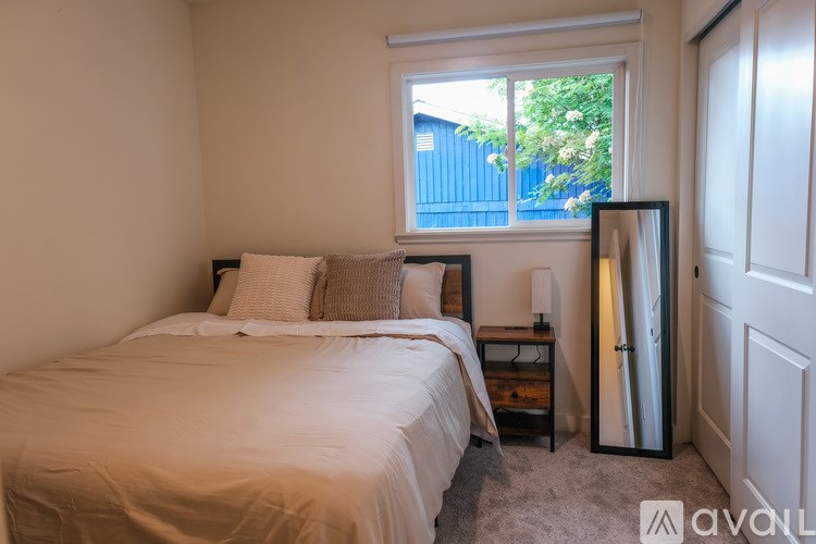 A bedroom with a bed, nightstand, and window.