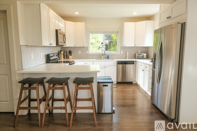 A kitchen with white cabinets and a wooden bar stool.