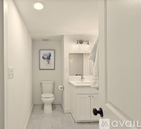 A white bathroom with a toilet, sink, and cabinet.