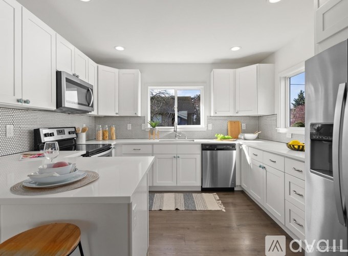 A modern kitchen with white cabinets and stainless steel appliances.
