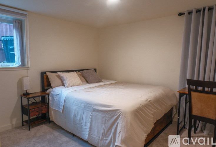 A bedroom with a bed, nightstand, and chair.