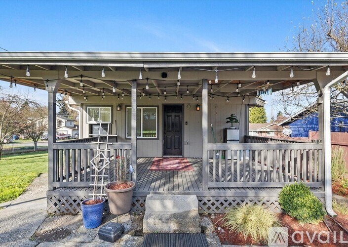 A house with a porch and a blue bucket on the ground.