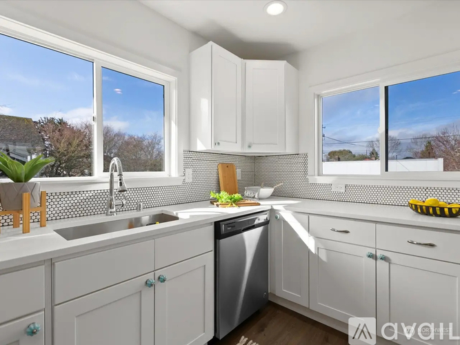 A modern kitchen with white cabinets and a dining table set for two.