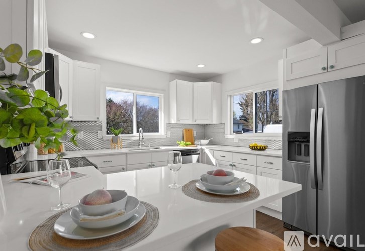 A modern kitchen with white cabinets and a dining table set for two.