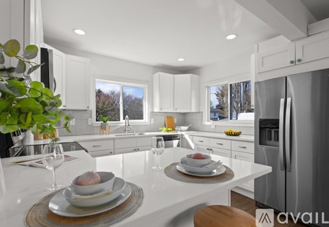 A modern kitchen with white cabinets and a dining table set for two.