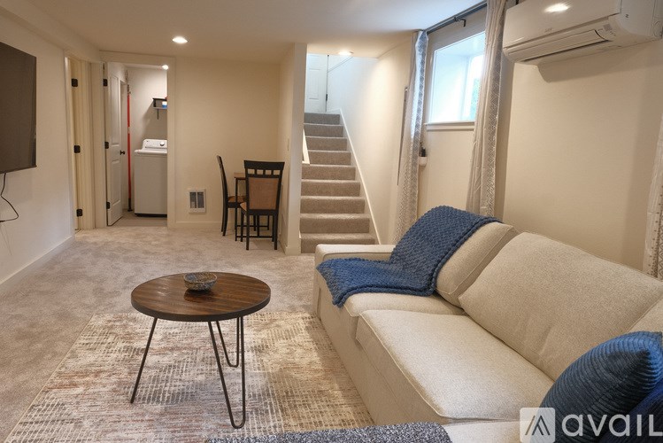 A living room with a couch, a table, and a staircase.