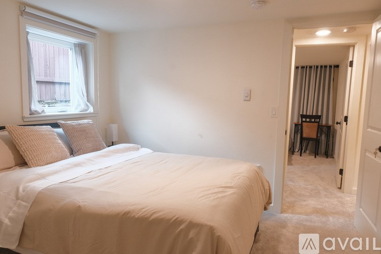 A bedroom with a large bed and a window with curtains.