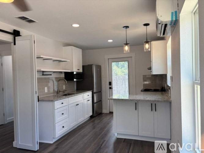 A kitchen with white cabinets and a window.