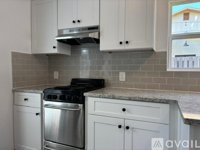 A kitchen with white cabinets and a stainless steel dishwasher and stove.