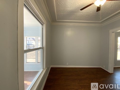 A room with a ceiling fan and a window overlooking a balcony.