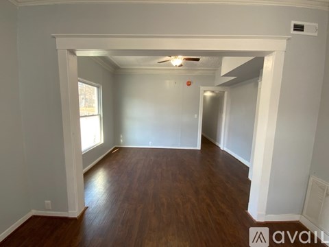 A spacious room with wooden floors and white walls.
