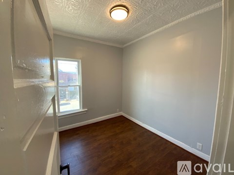 A room with a window and a wooden floor.
