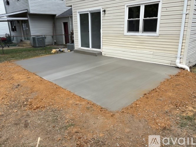 A concrete patio is being constructed in a backyard.