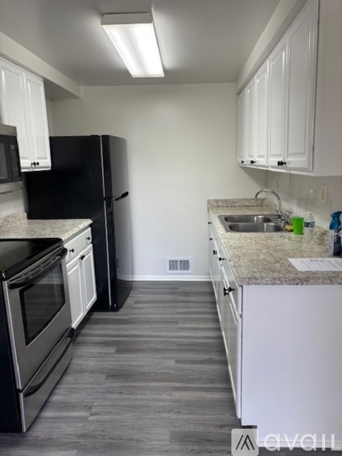 A kitchen with black appliances and white cabinets.