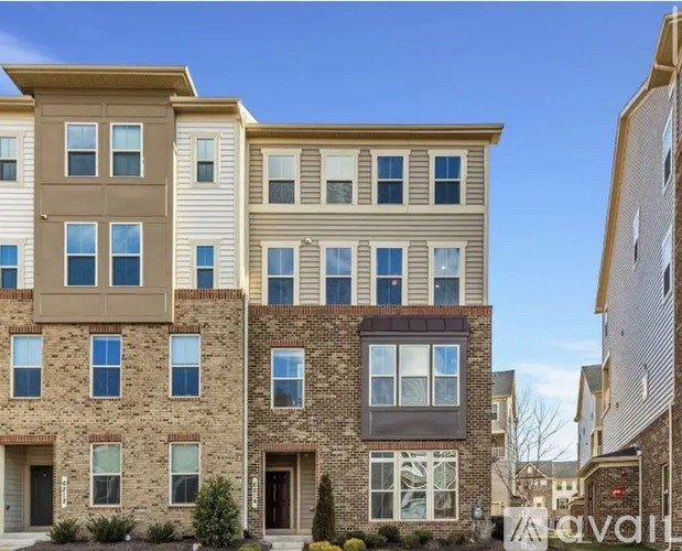 A row of modern townhouses with a clear blue sky above them.