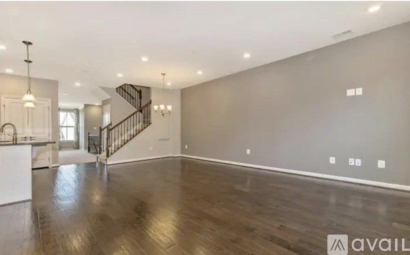 A spacious room with wooden flooring and a staircase with a metal railing.