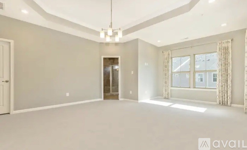 A spacious room with a chandelier and a door leading to another room.