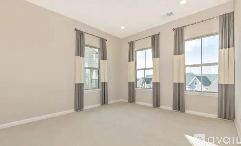 A spacious room with large windows and curtains.