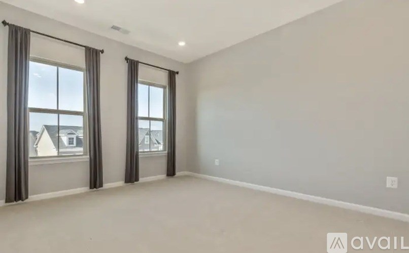 A room with two windows and a wall with a logo that says "available".