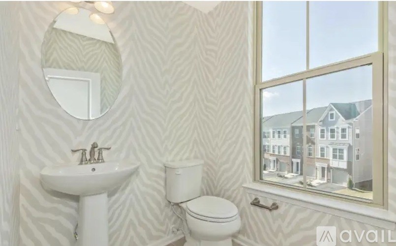 A bathroom with a white sink, toilet and wallpaper.