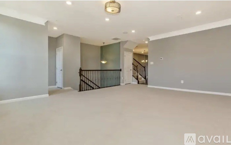 A spacious room with a staircase and a mirror on the wall.