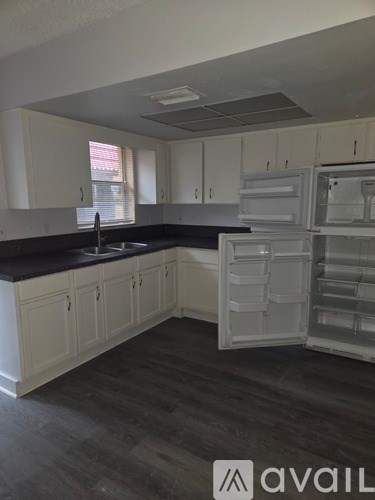 A kitchen with white cabinets and a black countertop.