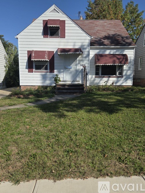 A white house with a red roof and a brown awning.